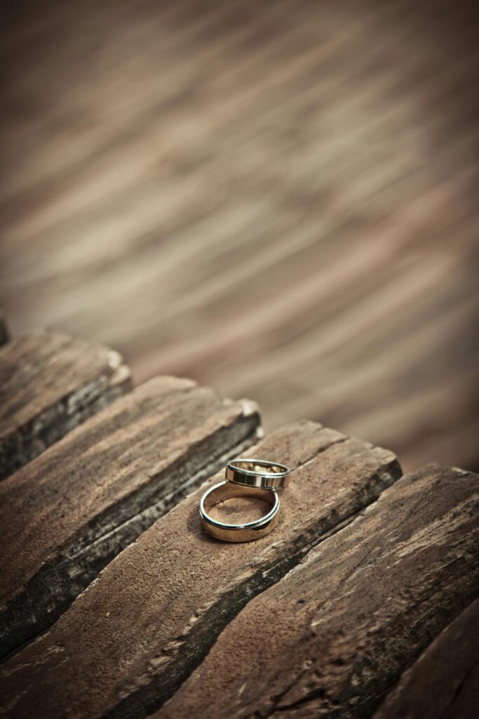 Close-up of elegant silver wedding rings on a rustic wooden surface, symbolizing love and unity.